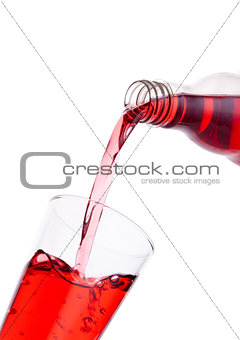 Pouring cranberry red juice from bottle to glass 