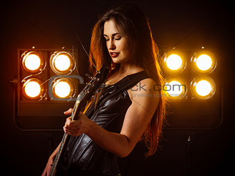 Sexy woman playing electric guitar on stage