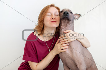 A woman with eyes closed hugging a dog