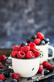 Fresh ripe blueberry and raspberry in mugs 