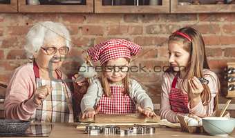 Grandma and granddaughters spreading dough