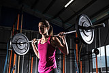 Athletic girl works out at the gym with a barbell