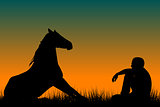 Horse and man silhouettes sitting on grass at sunset
