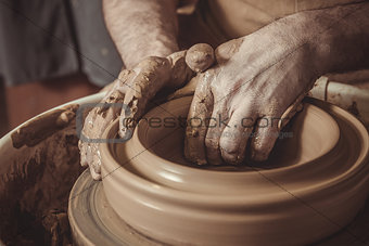 elderly man making pot using pottery wheel in studio