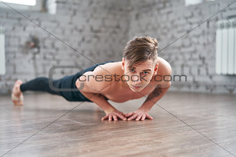 Athletic young man doing push ups on the floor