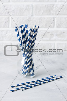 Glass jug with striped blue drinking straws brick wall backgroun