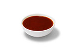 Red sauce in a gravy boat on white background