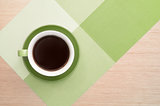 Green cup of coffee on the table background and tablecloth