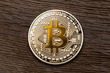 Golden yellow bitcoin on wooden background.