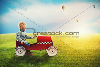 Child with car plays in a green field