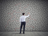 Businessman draws the solution of a labyrinth. Concept of problem solving