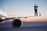 Businessman with binoculars over an aircraft searches for new business opportunities