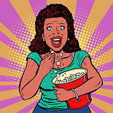 Woman watching a movie, smiling and eating popcorn