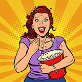 Woman watching a movie, smiling and eating popcorn