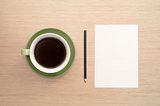 A green cup of coffee on the background of a table and a white shee and pencil