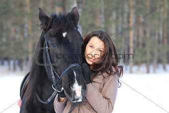 Portrait of a young black hair woman hugging a horse