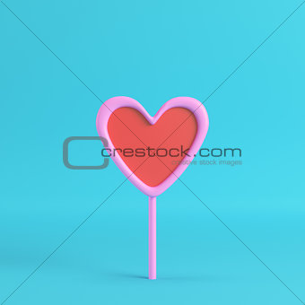 Pink with red heart on a stick on bright blue background