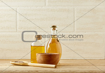 Composition of glass oil jars, wooden bowl with flax seeds, selective focus