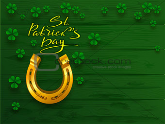 St. Patrick's day text greeting card. Golden horseshoe and green leaf clover trefoil on green board background