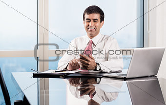 Senior manager in skyscraper office checking smart phone