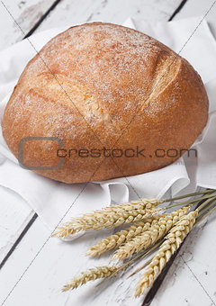 Freshly baked  bread with  kitchen towel and wheat
