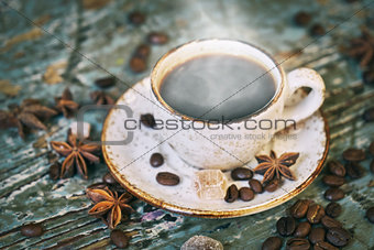 Cup of hot steaming coffee on the old scratched table