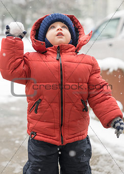 Boy looks upwards while snowing