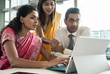 Three Indian employees working together around a laptop