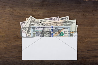 Dollar money in white envelop on wooden background.