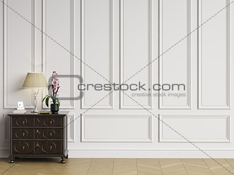 Classic sideboard with decor in classic interior with copy space.White walls with mouldings and ornated cornice. Floor parquet herringbone