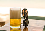 beer with high white foam transparent mug sunglasses outdoor cafe lunch on a hot day