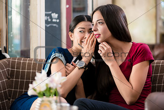 Young woman sharing secrets with her best friend