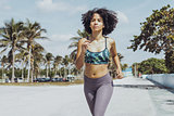 Black fit girl jogging on tropical waterfront