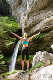 Active woman raising arms inhaling fresh air, feeling relaxed in nature.