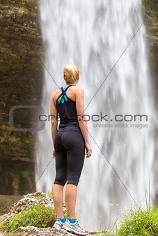 Active woman looking at Pericnik waterfall in Vrata Valley in Triglav National Park in Julian Alps, Slovenia.