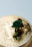 miniature man on a pile of bitcoins