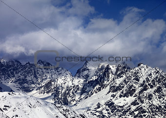 High snowy mountains in clouds at sunny day