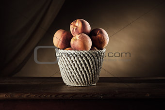 Ripe peaches in a basket still life