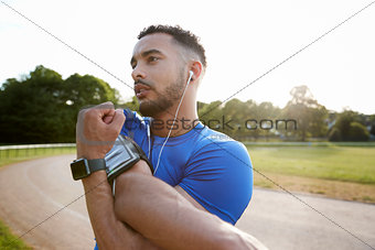 Male athlete at track stretching shoulders, close up
