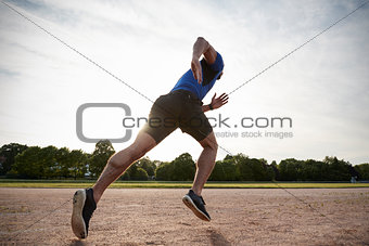 Young male athlete running at a track, low angle view
