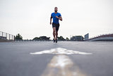 Male athlete running on a road towards camera, full length