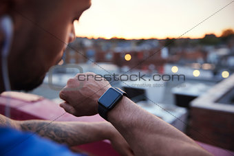 Male urban runner checks fitness app on smartwatch, close up