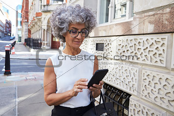 Middle aged woman using smartphone in city street