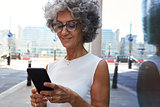 Middle aged woman using smartphone in city street, close up
