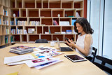 Woman in creative media office using smartphone at her desk