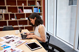 Woman in creative media office using laptop, horizontal