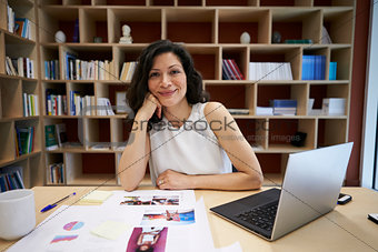 Middle aged female creative using laptop smiling to camera