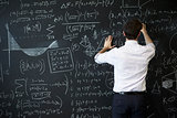 Young man writing on blackboard