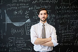Young man looking to camera in front of a blackboard