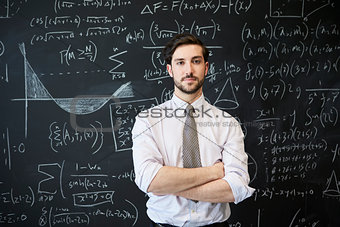 Young man looking to camera in front of a blackboard